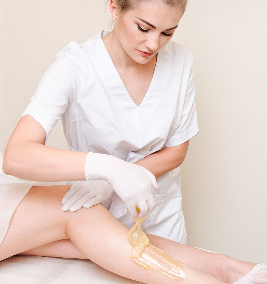Esthéticienne cosmétologue épilant les jambes des femmes dans le salon de beauté du centre de spa
