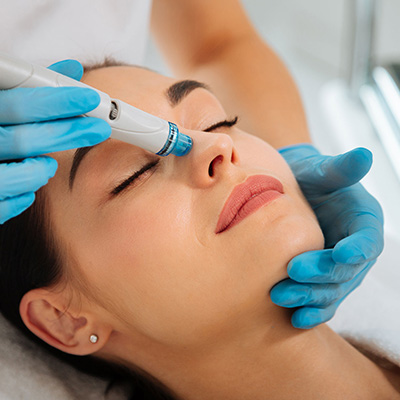 Beautiful woman receiving hydra-dermabrasion treatment by professional esthetician.