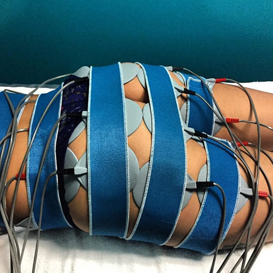 Woman lying down wrapped in Slimwave pulsating pads.