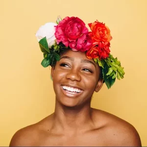 Young dark skinned woman wearing flowers on head open smiling